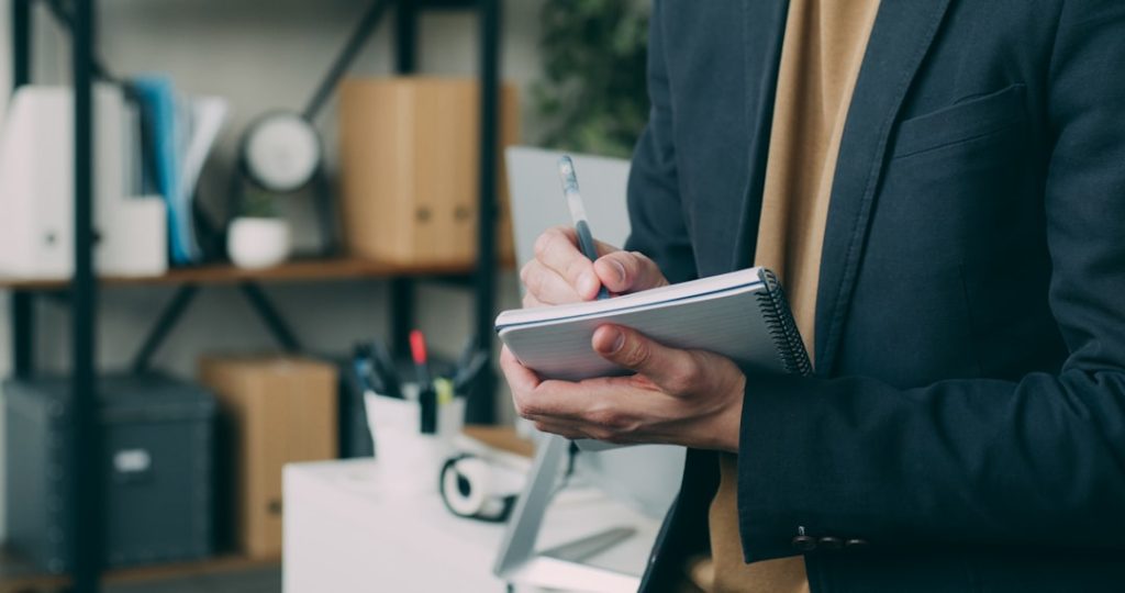 a-man-in-a-suit-writing-on-a-clipboard-9ih8j4vxcgo